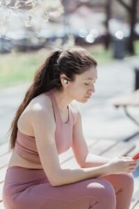 Woman with earbuds listening to an audiobook on her smartphone