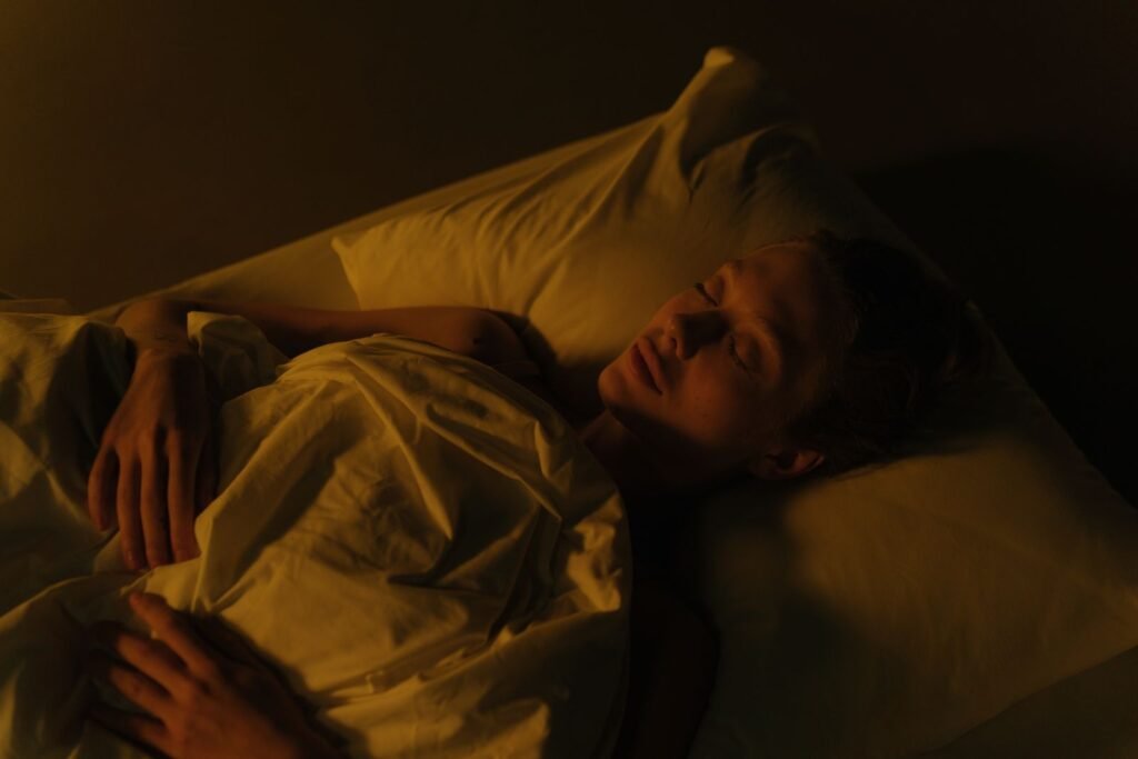 Woman sleeping under a blanket in a dim bedroom at night