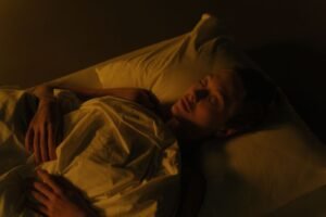 Woman sleeping under a blanket in a dim bedroom at night