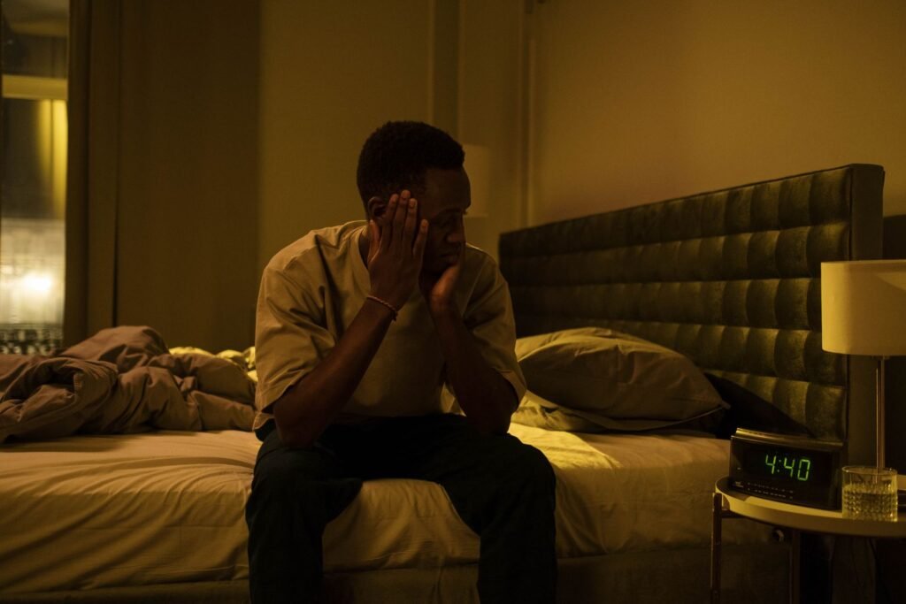 Man sitting on the edge of his bed at night