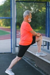 Senior man stretching his knee outdoors