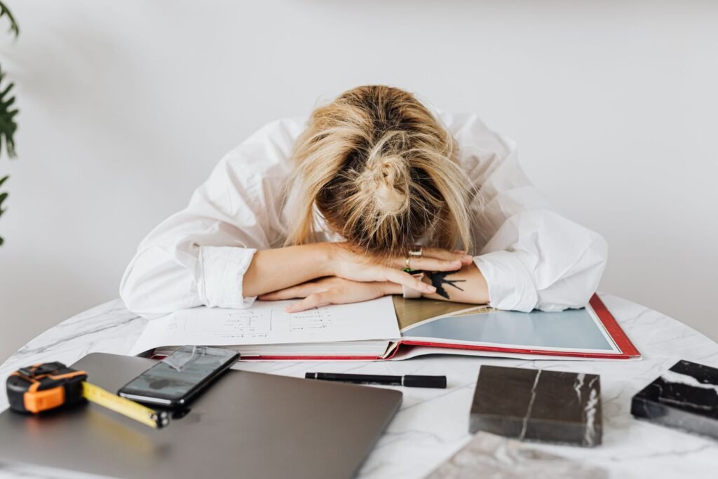 Exhausted woman resting her head on a desk — a sign of not getting enough deep sleep