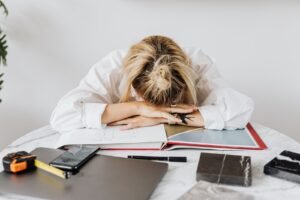 Exhausted woman resting her head on a desk — a sign of not getting enough deep sleep