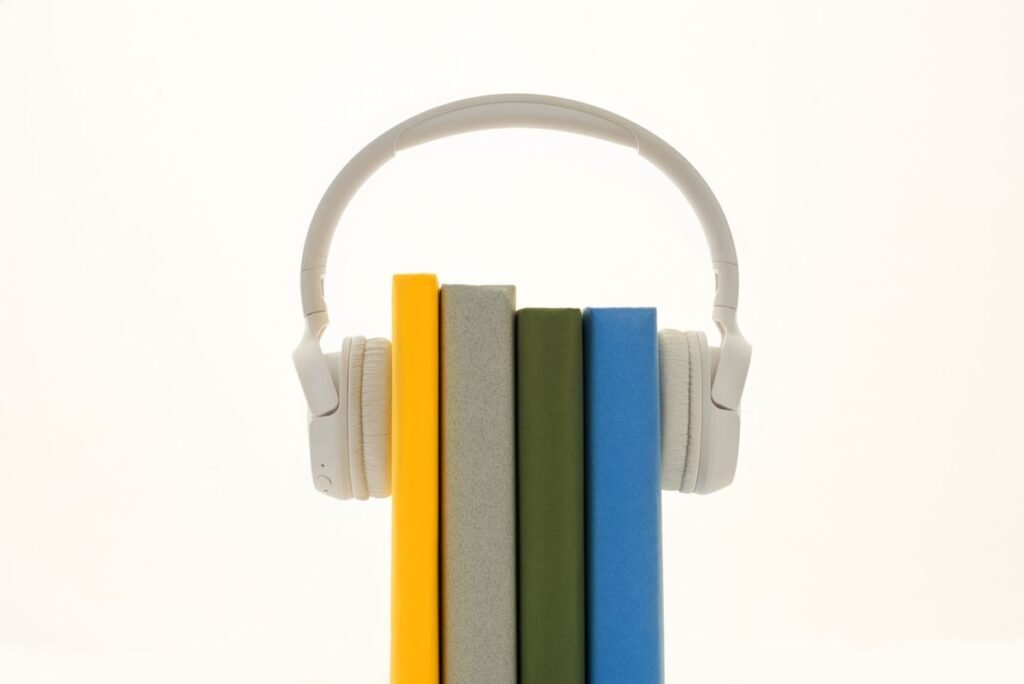 White headphones resting on books, audiobook listening